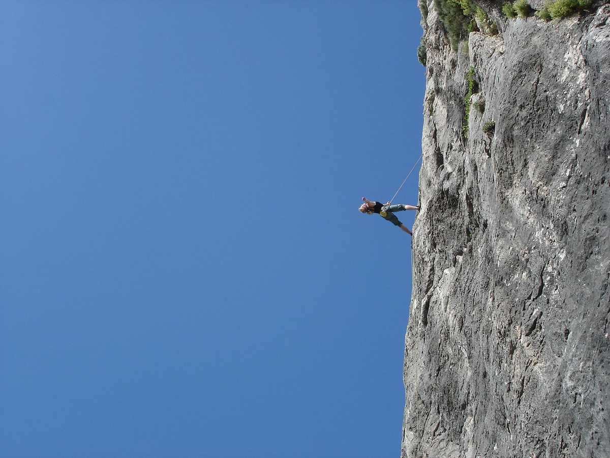 Personne en escalade sur une falaise rocheuse, ciel bleu sans nuages Personne en escalade sur une falaise rocheuse, ciel bleu sans nuages