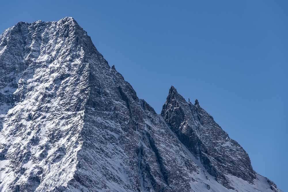 Pics de montagne enneigés sous ciel bleu, sans végétation ni traces d'activité humaine Pics de montagne enneigés sous ciel bleu, sans végétation ni traces d'activité humaine